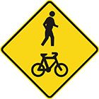yellow diamond-shaped sign with a black icon of a human figure walking and a bicycle