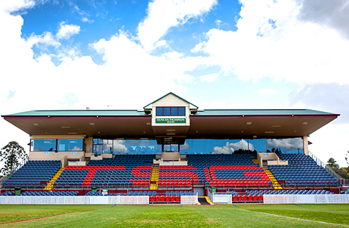 Townsville Sports Ground outdoor stadium with rows of colored seats and a green grass field in the foreground