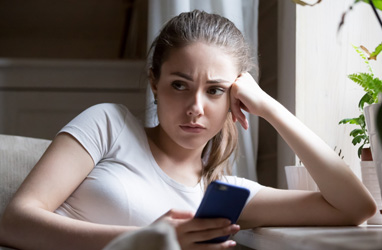 Young girl holding her phone looking concerned