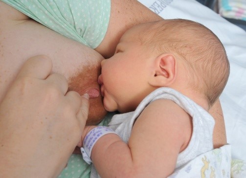 Baby at the breast with nipple being removed from baby&rsquo;s mouth by the mother.