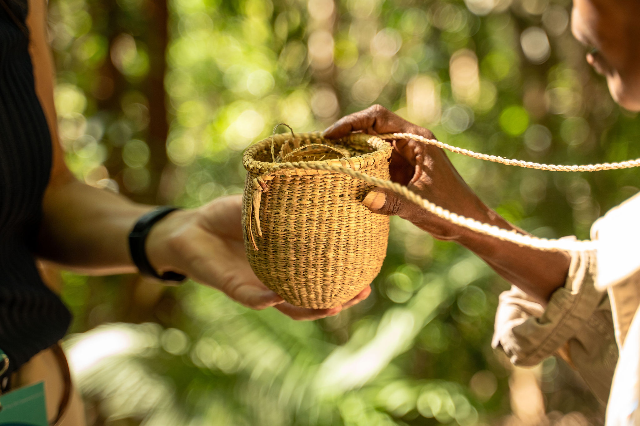 Hands hold a traditionally woven basket