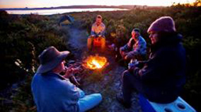Campers sitting around a camp fire.