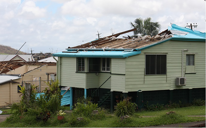 Photo of houses with roof and wall damage after a cyclone