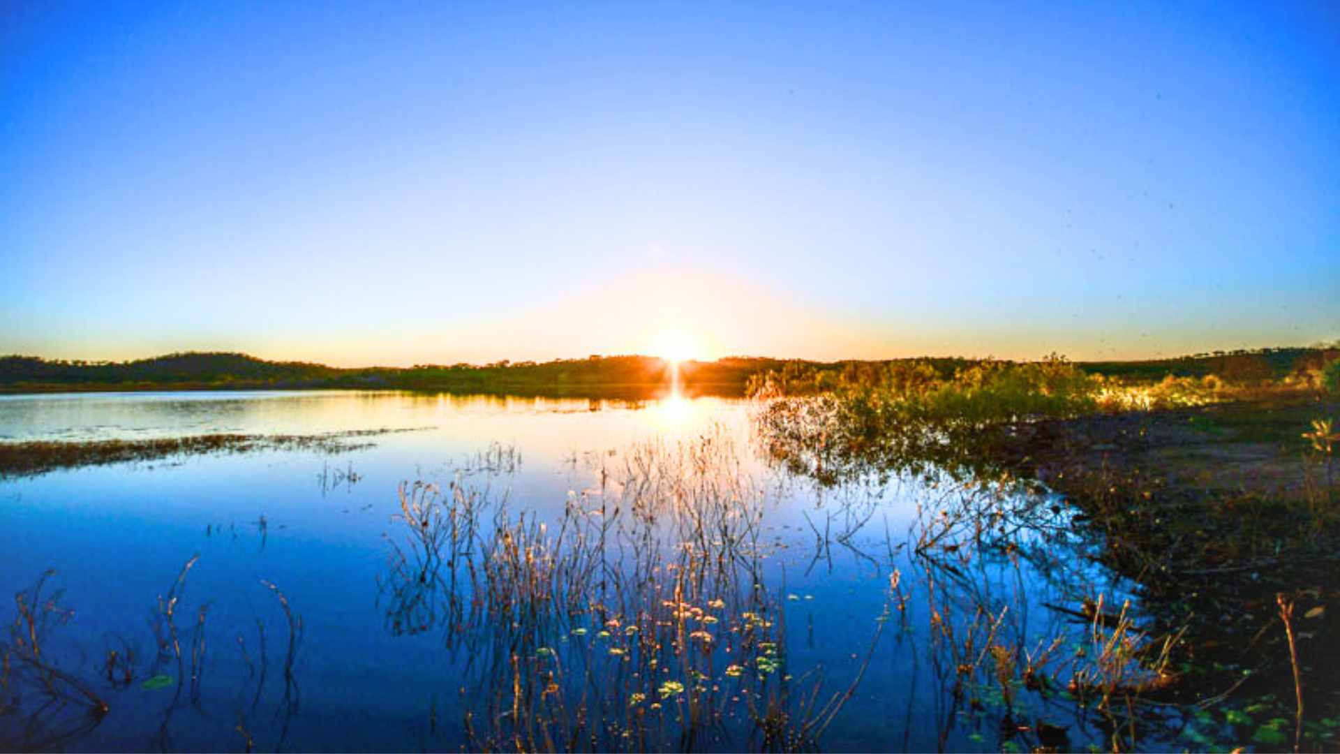 Sunset over Lake Belmore with still water reflecting the horizon.