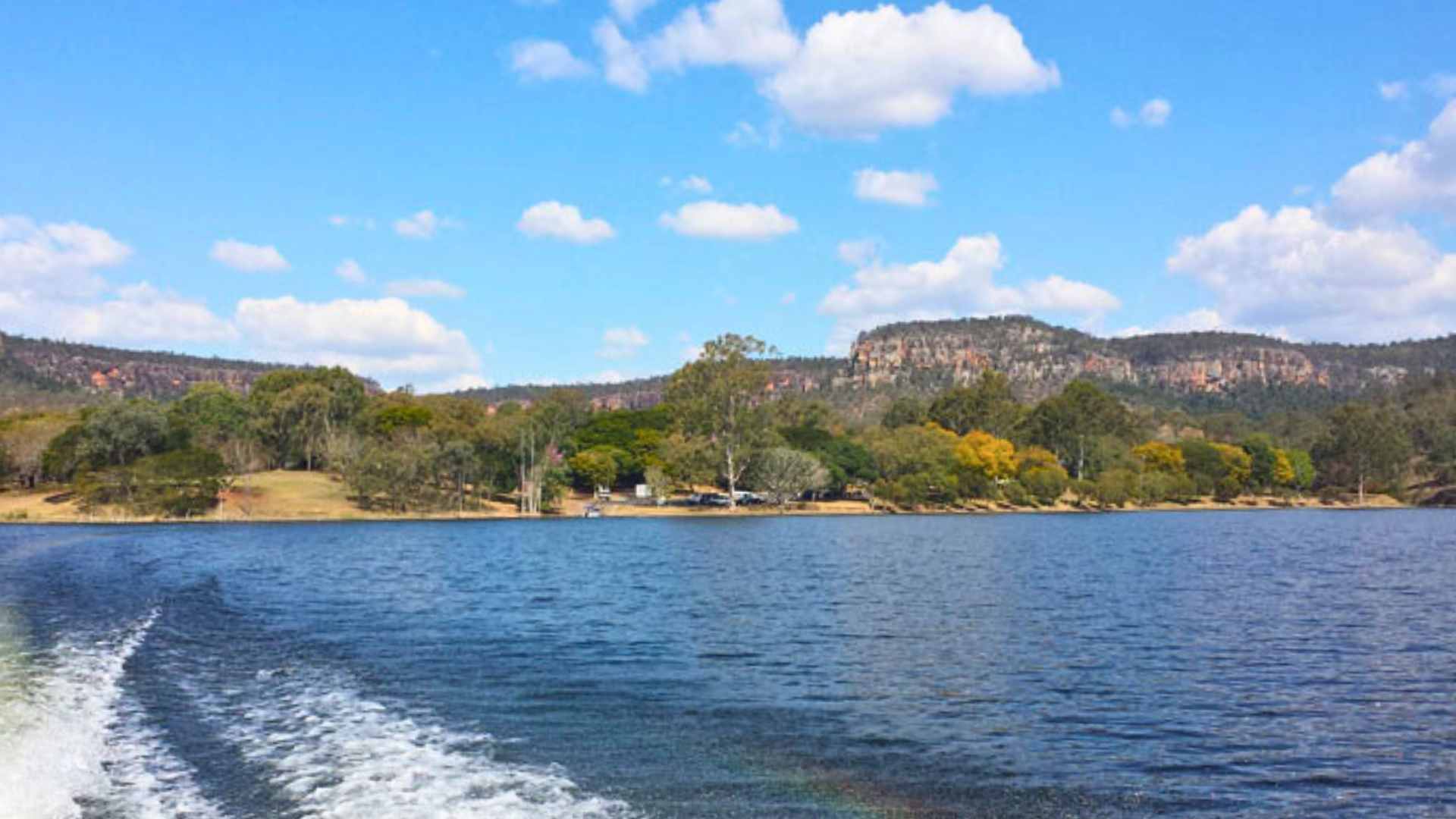 Open water of Cania Dam with bushland and sandstone cliffs in the distance.