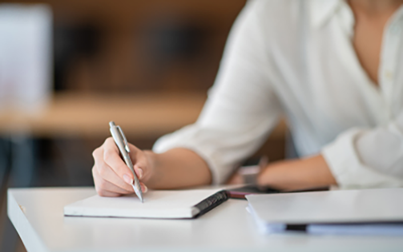 torso of a person sitting down writing