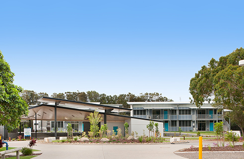 Exterior view of the venues building, with paved paths and surrounding green trees. 