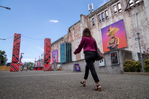 a person walking in front of a building with colourful banners